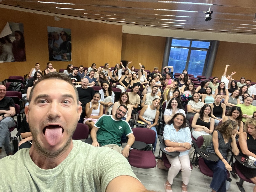 Teaching a classroom of design students at HIT/Reichman University — tiered lecture hall with a full group seated in rows